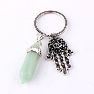 Detail of silver Hamsa hand charm and light green hexagonal crystal pendant on keychain