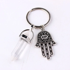 Macro shot of crystal hexagonal prism and Hamsa hand pendant on a silver keychain