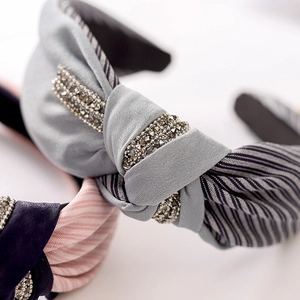 Close-up of a knotted fabric headband with elegant stripe patterns and sparkling rhinestones