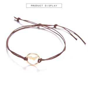 Dettaglio del bracciale in corda marrone intrecciata con ciondolo montagna dorato