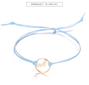 Dettaglio del bracciale a corda intrecciata blu con ciondolo a montagna dorato e nodo scorsoio