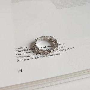 Detailed close-up of silver crisscross ring with zircons on an artistic book page