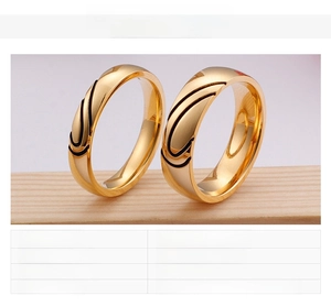 Detail of 18K gold plated couple rings with black swirl texture on wooden stand