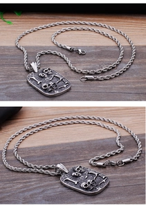 Detail of vintage silver skull pendant on wooden background with braided chain