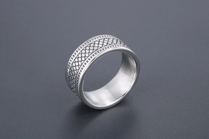 Détail de la bague large en acier vintage à motif damier avec bords perlés sur fond sombre
