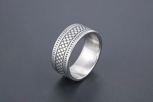 Vue macro d'une bague en acier argenté avec texture grillagée et bords perles