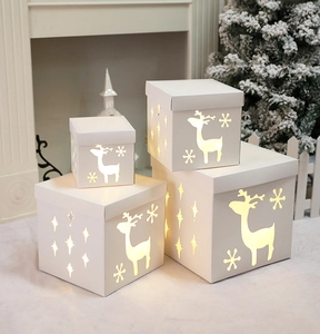 Macro detail of white hollowed Christmas gift boxes with warm LED lights and reindeer patterns