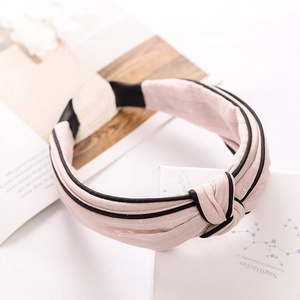 Pink knotted wide headband with black trim on a white decorative card with book