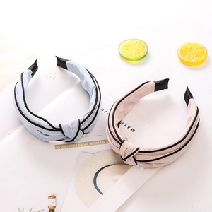 Detail of pink and light blue knotted headbands with black trim on aesthetic background