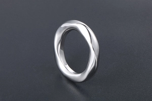 Gros plan d'une bague tordue en acier titane argenté avec finition miroir polie
