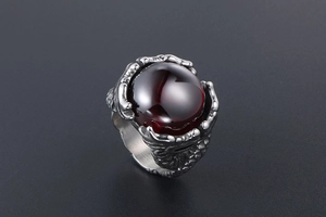 Macro view of vintage dragon claw ring with a large red gemstone in silver finish