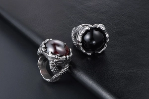 Detail view of dragon claw rings featuring polished black and red gemstones on black leather