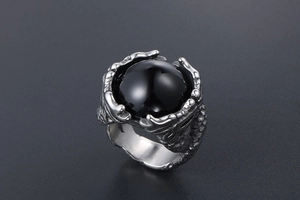 Macro shot of silver dragon claw holding a large round black gemstone on titanium steel ring