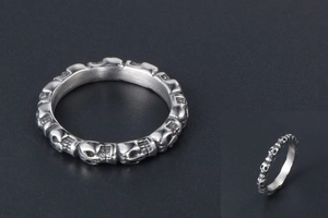 Detailed macro shot of silver titanium steel ring with carved skull motifs and polished finish