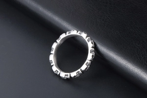 Macro shot of a silver titanium steel skull ring band on black leather texture background