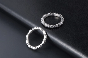 Close-up of two silver titanium steel rings with continuous skull relief design on black leather