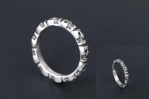 Macro view of vintage silver skull relief ring showing detailed antique engraving