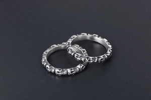 Detailed view of two silver titanium steel rings with continuous skull pattern engraving