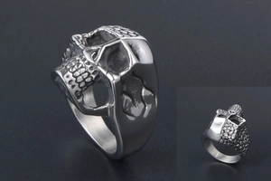 Macro detail of silver titanium steel skull ring showing embossed punk rock textures