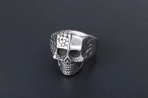 Macro shot of titanium steel skull ring featuring half scales and half smooth metal finish