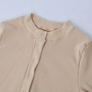 Dettaglio del body in maglia a costine beige con scollo rotondo e bottoni a pressione argento