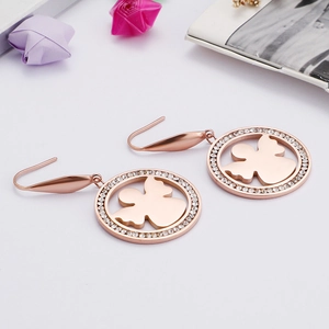 Boucles d'oreilles ange en titane or rose avec cristaux sur fond élégant et épuré