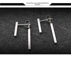Close-up of polished silver stainless steel rectangular bar drop earrings on black texture