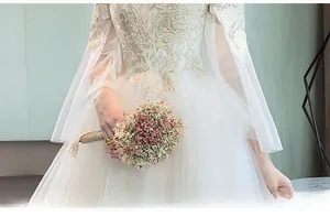 Detail of white wedding dress featuring intricate gold vine embroidery and sheer lace sleeves