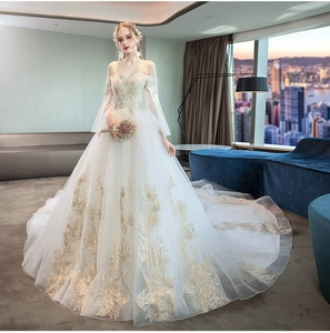 Detail of luxury bridal gown showing gold floral embroidery and long off-shoulder sleeves