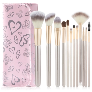 Close-up of 12 makeup brushes with champagne gold handles and a pink printed leather pouch