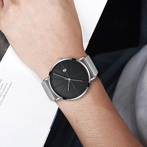 Detail of silver mesh band watch with minimalist black dial and date window on wrist