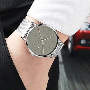 Close-up of minimalist silver mesh watch band and dark grey dial on man's wrist