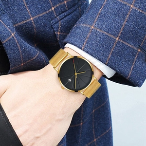 Close-up of a men's business watch with black dial and gold mesh strap on a suit
