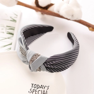 Gray striped knotted headband with rhinestone accents on a minimalist white display