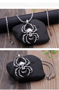 Close-up of a punk skull spider pendant in silver stainless steel on dark rock textures