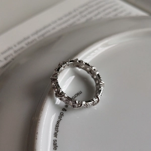Close-up of 925 sterling silver ring with pavé-set stones on a white ceramic plate