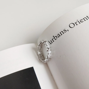Minimalist 925 sterling silver band ring with sparkling cubic zirconia on a book page