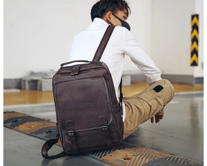 Male model wearing dark brown vintage PU leather backpack in a minimalist setting