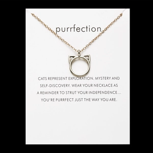 Close-up of cat-ear pendant necklace with 'Purrfection' card and meaningful quote