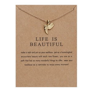 Golden hummingbird pendant necklace displayed on a brown Life is Beautiful gift card