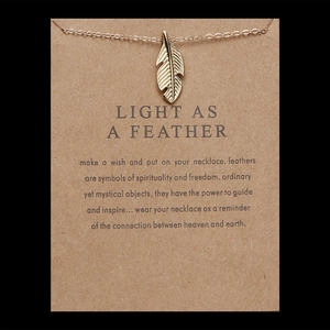 Detailed close-up of a gold feather pendant necklace on a LIGHT AS A FEATHER message card