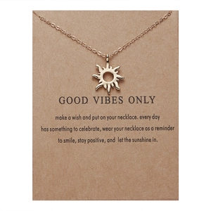 Close-up of gold sun pendant necklace on a brown gift card package for positive vibes