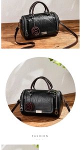 Close-up of black retro cylinder pillow bag with red rose pendant and detachable strap