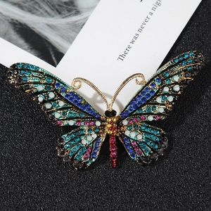 Detailed close-up of butterfly brooch with blue and purple rhinestones on a golden base