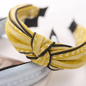 Macro detail of yellow knot headband with leaf pattern and refined fabric texture