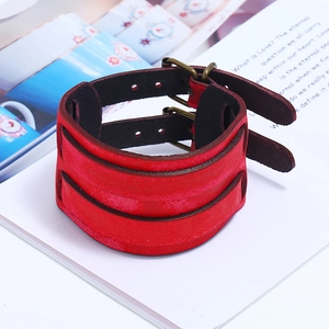 Detail of red leather wide cuff bracelet with bronze buckles on a vintage book