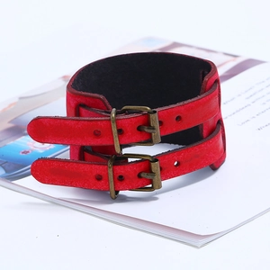 Vintage red leather wide cuff bracelet with bronze buckles on a magazine backdrop