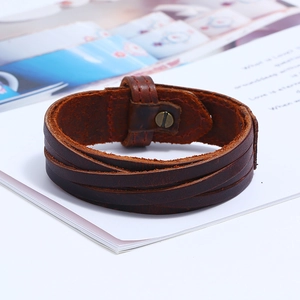 Macro detail of multi-layer brown braided leather bracelet with vintage bronze snap button