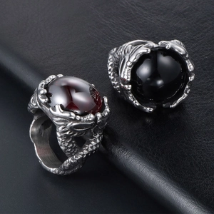 Vintage dragon claw rings with red and black gemstones on a textured black surface