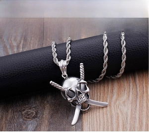 Dettaglio di un ciondolo punk teschio argento vintage con spade incrociate e catena